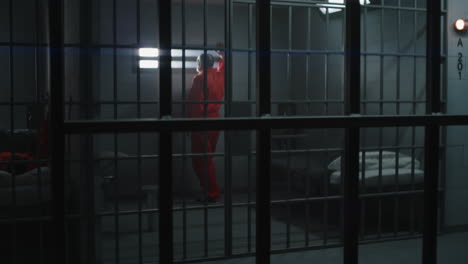 Elderly-Prisoner-Leans-on-Metal-Bars-and-Looks-at-Camera