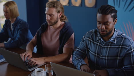 multi ethnic business people typing on laptops in coworking.