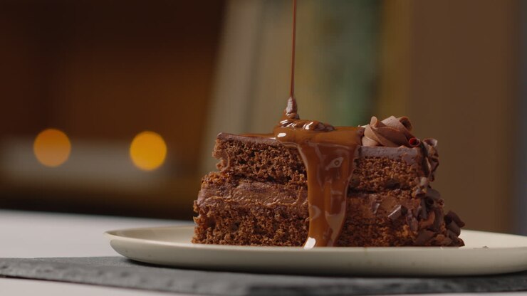 Person Pouring Melted Chocolate Sauce On Slice Of Chocolate Cake Before Eating It With A Fork 1