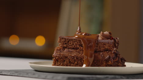 person pouring melted chocolate sauce on slice of chocolate cake before eating it with a fork 1