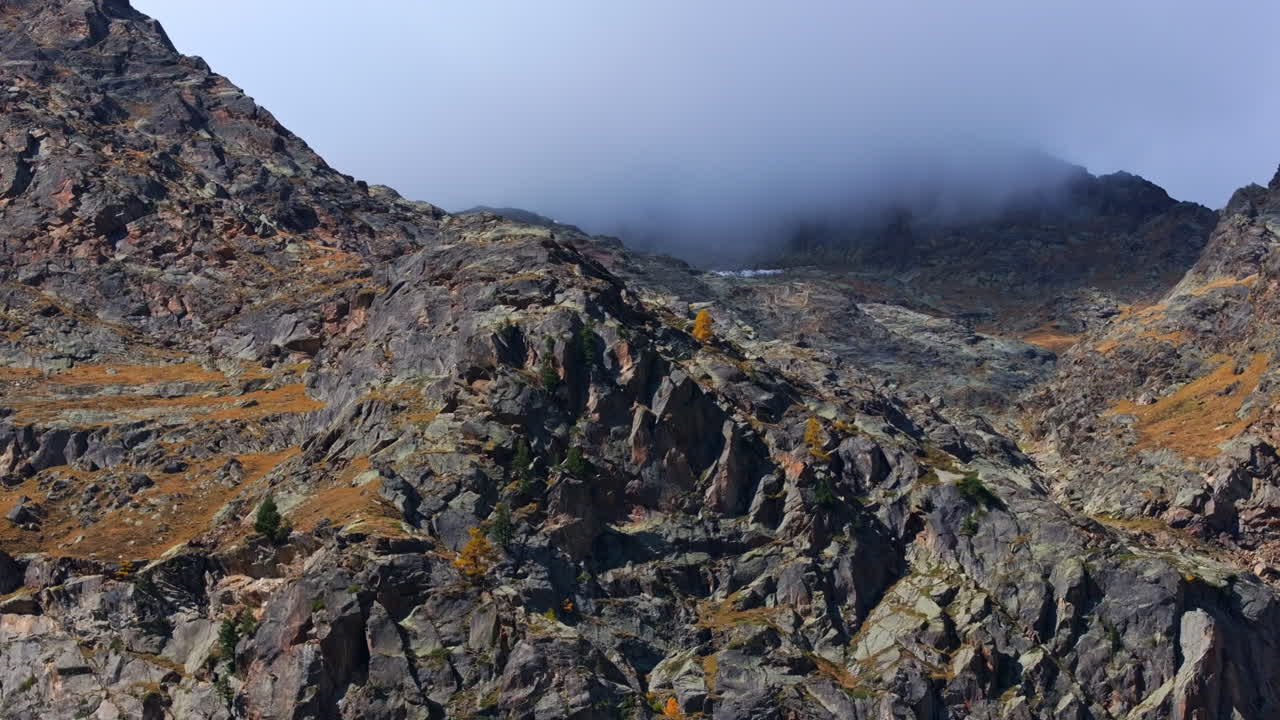 Stunning aerial footage of Saas-Fee in autumn. Golden forests surround the alpine village, nestled in the Swiss Alps. Vibrant fall colors and majestic peaks highlight the beauty of the season.
