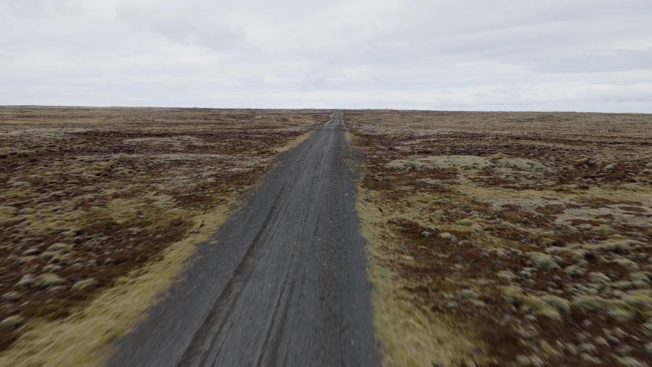 La strada Reykjanesvitavegur 443 attraversa un terreno vulcanico brullo verso Reykjanesviti, Reykjanesbaer, Penisola Meridionale, Islanda, durante un sorvolo in avanti con drone.