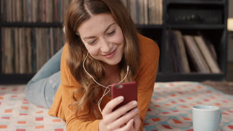 Hermosa-Mujer-Feliz-Y-Sonriente-En-Casa-Usando-Un-Teléfono-Inteligente-Con-Pantalla-Táctil-Escuchando-Música-En-Un-Apartamento-Retro