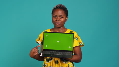 Young-adult-showing-a-laptop-with-isolated-mockup-screen-in-studio