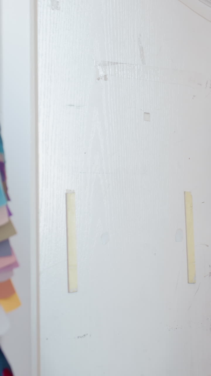 Donna bianca che seleziona campioni di colore alla porta, designer che consulta un cliente con un rack di strisce di tessuto, texture tattili e tonalità vivaci, scatto di profilo spontaneo in uno studio d'interni, palette collaborativa