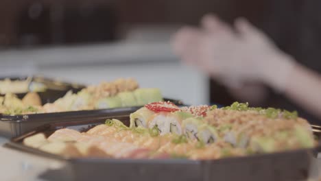 dolly movement towards take away sushi with the chef working in the blurred background. slow motion in 25fps.