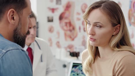 Handheld view of young couple and gynecologist in doctor&rsquo;s office