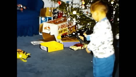 Young Boy Standing in Front of Christmas Tree. CIRCA USA - 1970s: A young boy stands proudly in front of a festively decorated Christmas tree, showcasing his joyful holiday spirit.