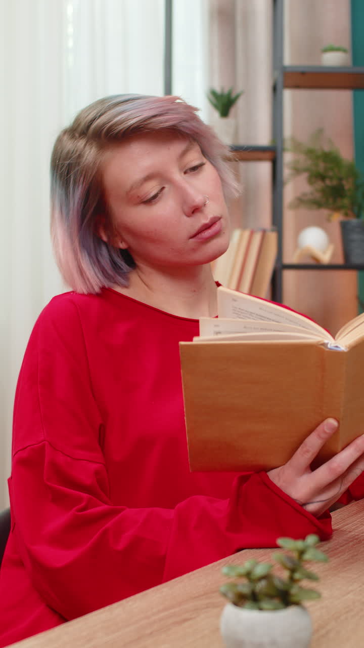 Young woman thoughtfully reading book turning pages concentrated serious expression literature hobby