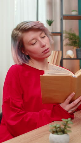 young woman thoughtfully reading book turning pages concentrated serious expression literature hobby