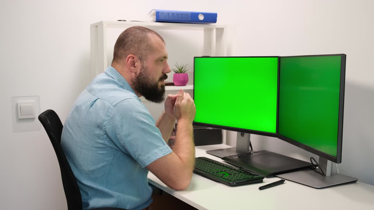hombre escribiendo en el teclado en dos monitores con la pantalla verde. trabajo remoto en casa