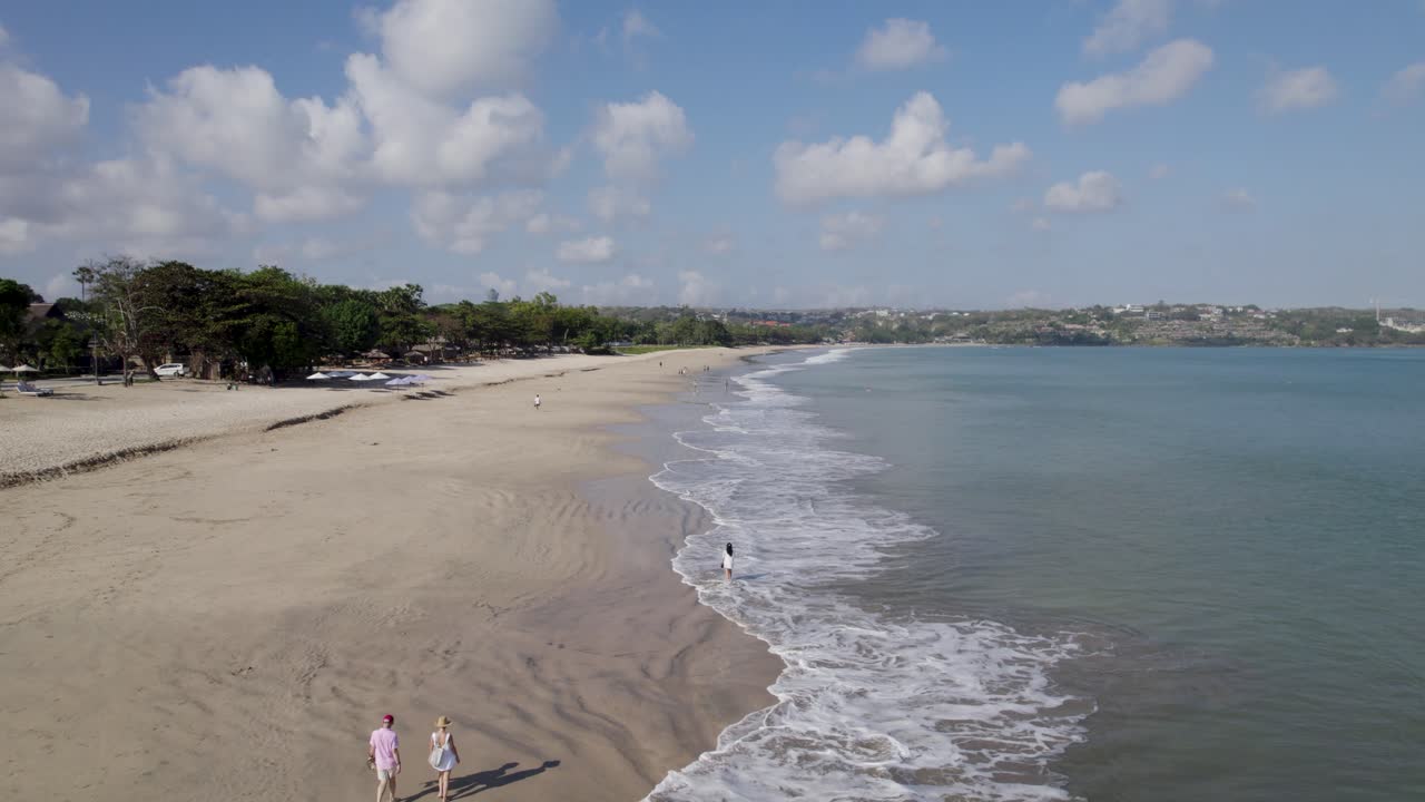 video aéreo en la playa de jimbaran en bali, denpasar, indonesia durante un día soleado con olas calmantes del mar.
