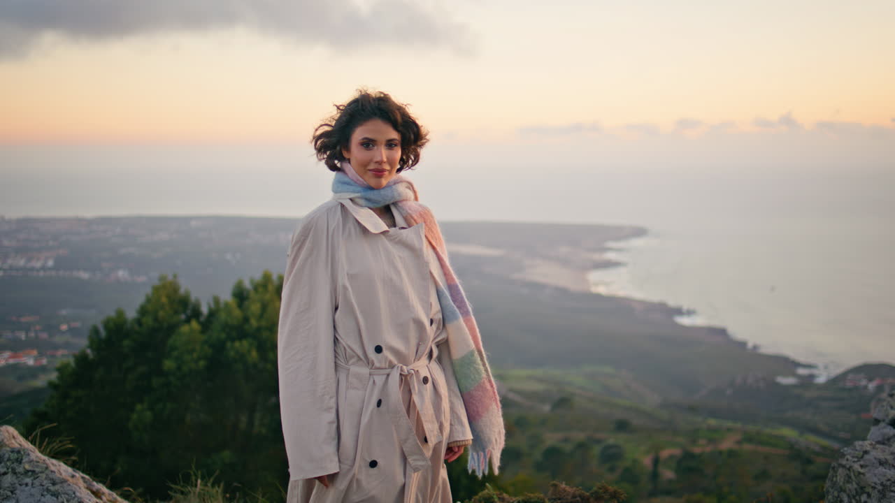 Elegantes Model posiert vor Sonnenuntergangshimmel und strahlt gelassene Schönheit aus. Lockige Frau an der Küste.