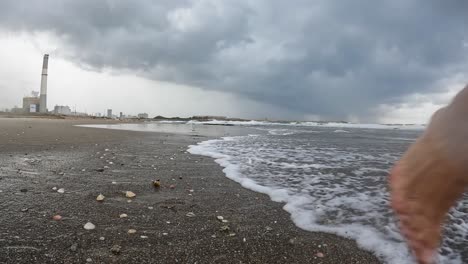 long-haired man running on the beach while on holiday with beautiful waves with an amazing sky and clouds in the background