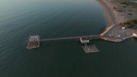 vista aérea en cámara lenta de cabañas de pesca a orillas del estuario al atardecer, máquina de pesca italiana, llamada "trabucco", lido di dante, ravenna cerca del valle de comacchio