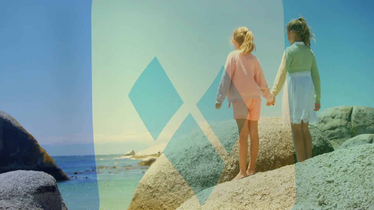 Holding hands, two children on rocks by ocean with animation overlay
