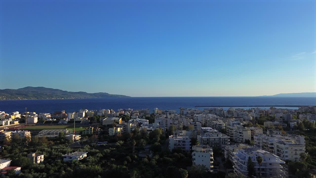 Aerial tilt up, push in shot, revealing Messinian gulf over Kalamata cityscape 4K. Greece, Peloponnese on a clear blue sky day