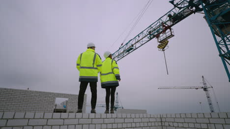 two civil engineers are viewing construction site male and female figures against building crane