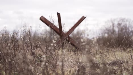 rusty old anti-tank barrier in the meadow against the sky