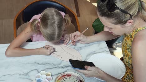 madre e hija pintando una placa de cerámica