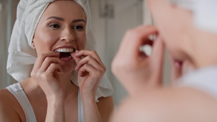 Woman applying a transparent dental aligner in the bathroom.