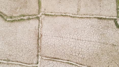 dry cracked drought fractured agricultural land sections aerial view above barren damaged landscape