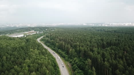 aerial view of a road winding through a forest, leading to a city