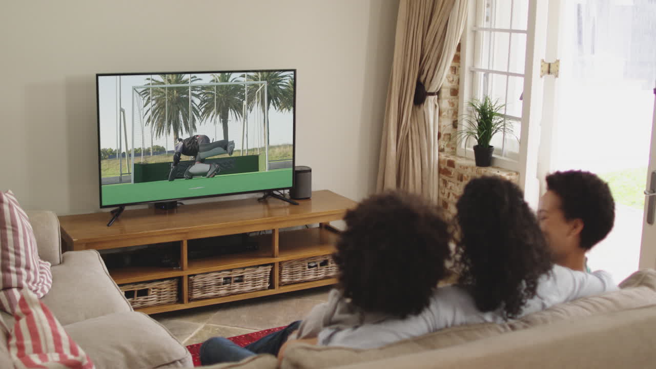 Famiglia felice seduta a casa insieme che guarda una partita di hockey in TV