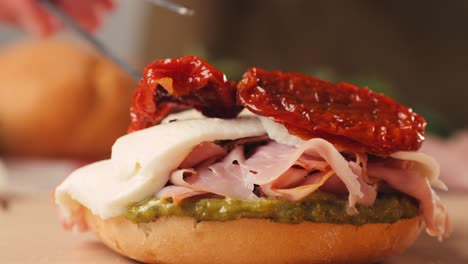 mortadella ham sandwich, traditional italian focaccia filled with thin pesto slices of mortadella, served by chef man in cafe restaurant. macro of traditional italian spanish tapas antipasti.