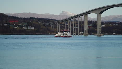 un bateau de pêche passant sous le pont près de l'île de senja, norvège