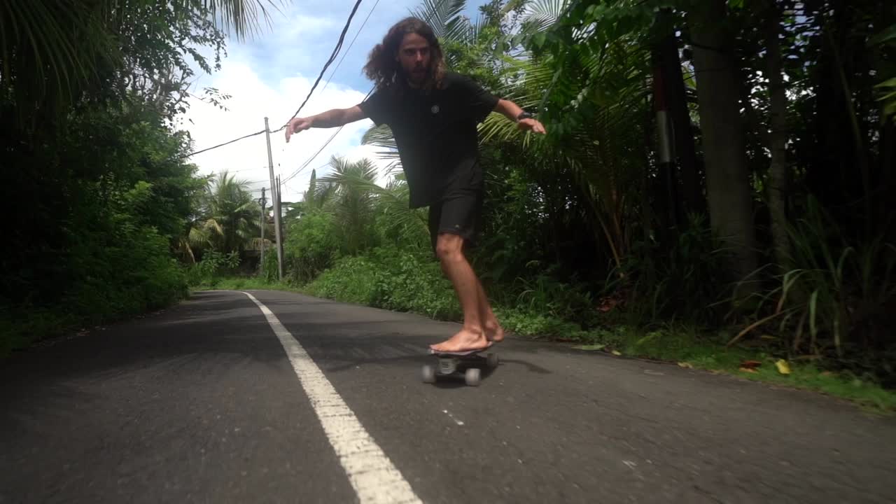 elegante patinador montando en surf skate en las carreteras de bali, estilo de vida skate