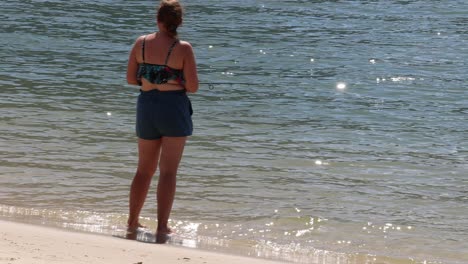 a woman stands by the water's edge