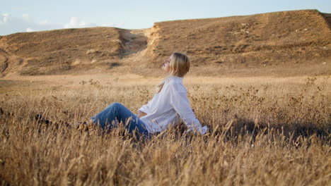 Nachdenkliches-Mädchen,-Das-Allein-Auf-Dem-Feld-Sitzt.-Vertikal-Blonde-Frau,-Die-Ährchen-Setzt