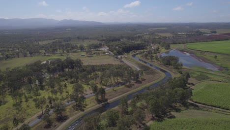canalice el agua que fluye a través de campos con árboles verdes en la ciudad rural de arriga cerca de walkamin en el norte de queensland, australia
