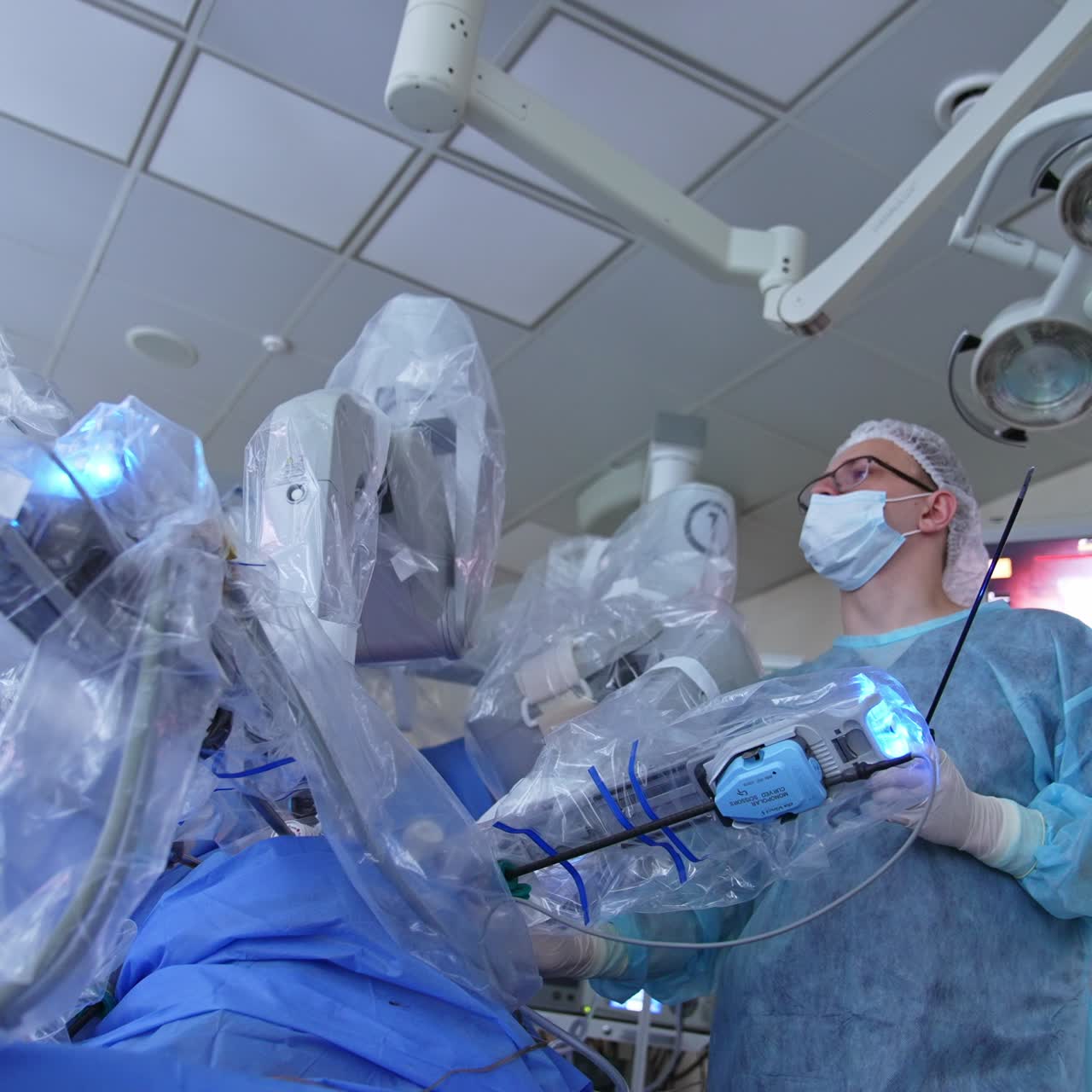 Surgeon holding the hand on a patient being operated by Da Vinci robot. Controlling the surgery watching it on the screen. Low angle view