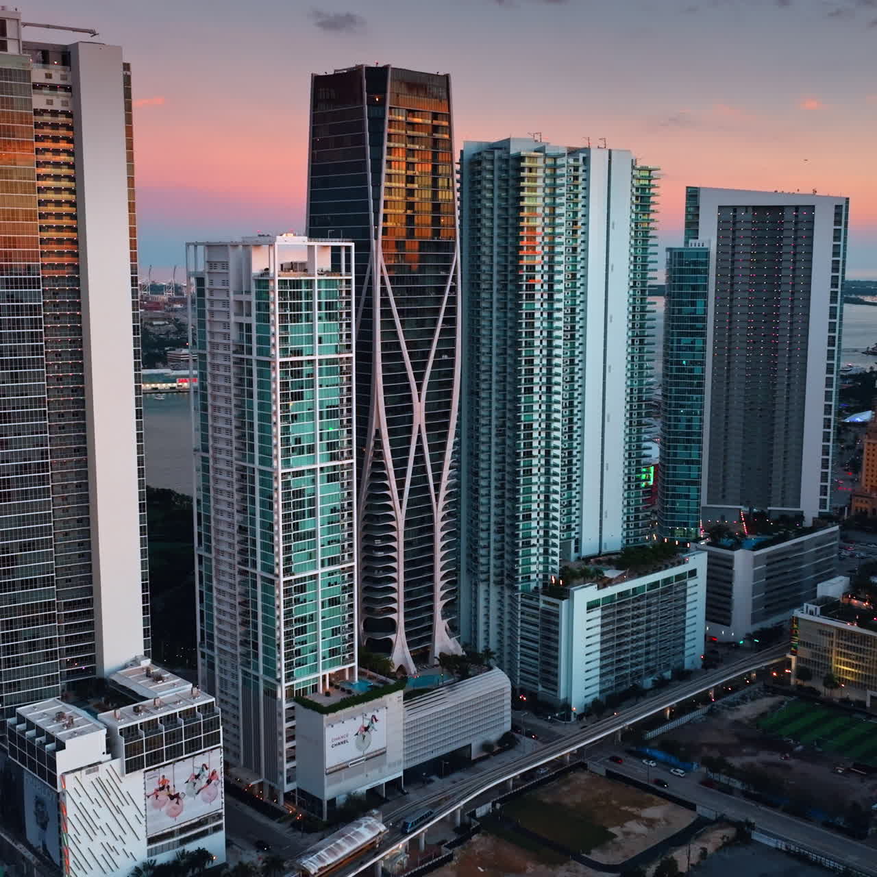 Approaching the group of skyscrapers standing close to each other. High-rise building in rays of setting sun in Miami, Florida, United States.