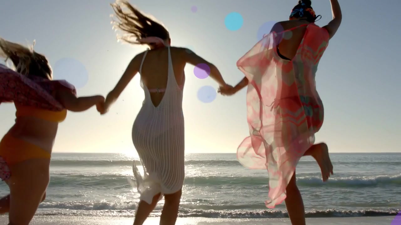 Tre donne che si tengono per mano correndo verso le onde al tramonto, contenuto lifestyle con bagliori dell'obiettivo.