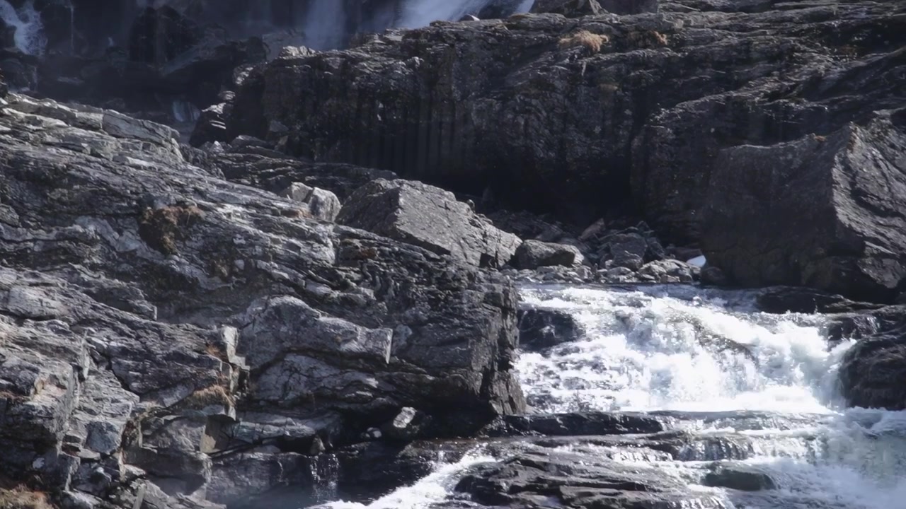 Cascading Kjosfossen waterfall flows over rugged rocks in bright daylight, Norway Europe