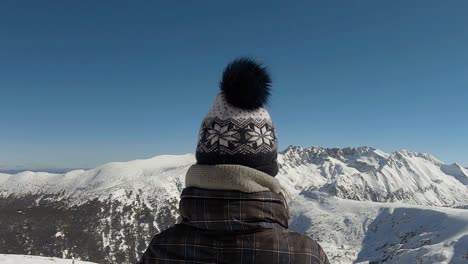 Girl-looking-at-a-horizon-of-mountains-covered-with-snow-in-front-of-her-in-Bansko,-Bulgaria