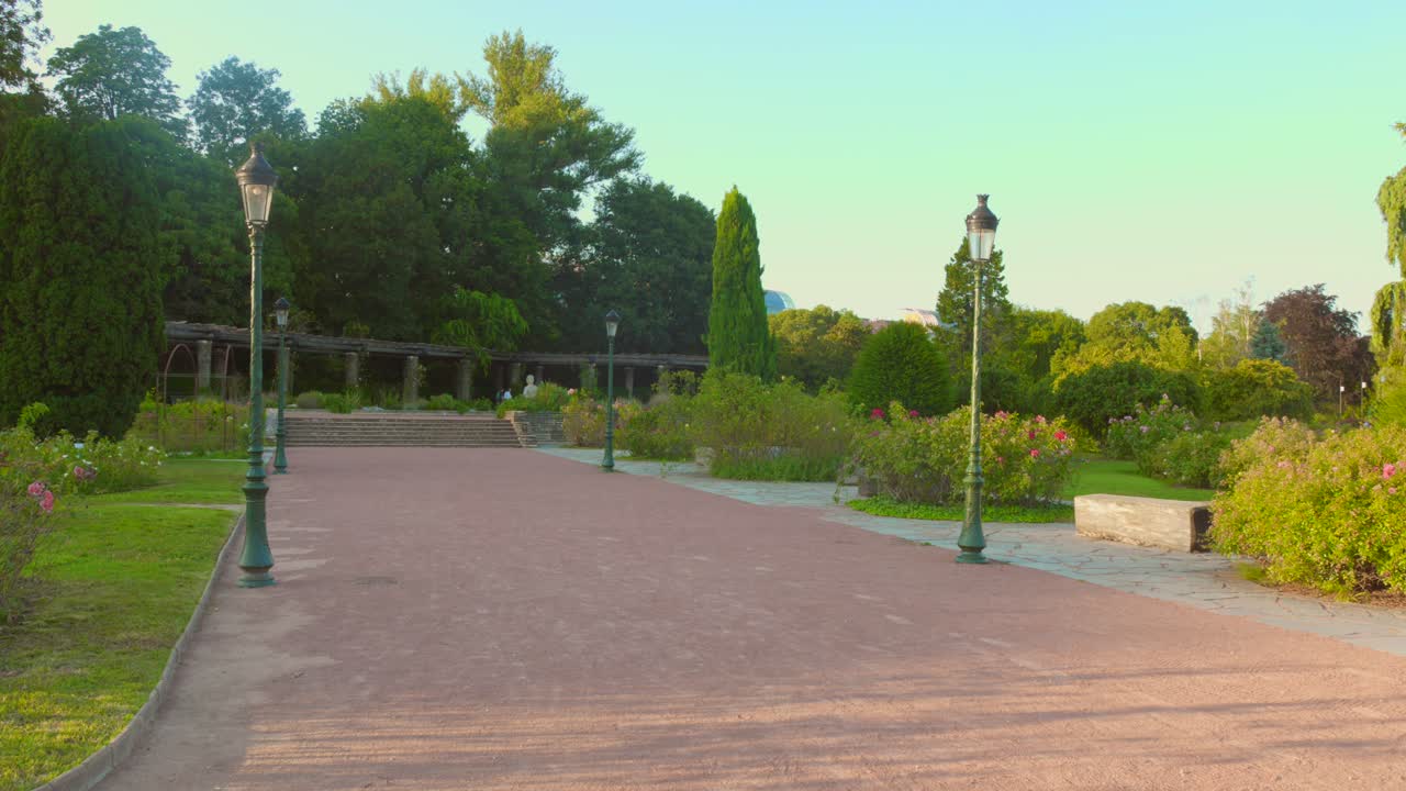 Experience a peaceful stroll along the pathways of the Park of the Golden Head in Lyon as golden hues fill the sky during a tranquil evening.