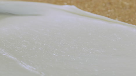 Close-up-of-a-spatula-spreading-out-icing-on-a-large-scale-factory-sized-cake-bake