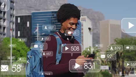 animación de iconos de redes sociales sobre un feliz hombre afroamericano usando un teléfono inteligente en la calle
