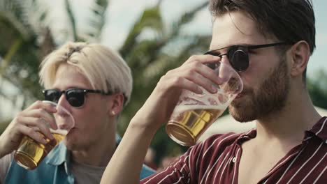 twee jonge blanke mannen die plezier hebben op een muziekfestival terwijl ze bier drinken.