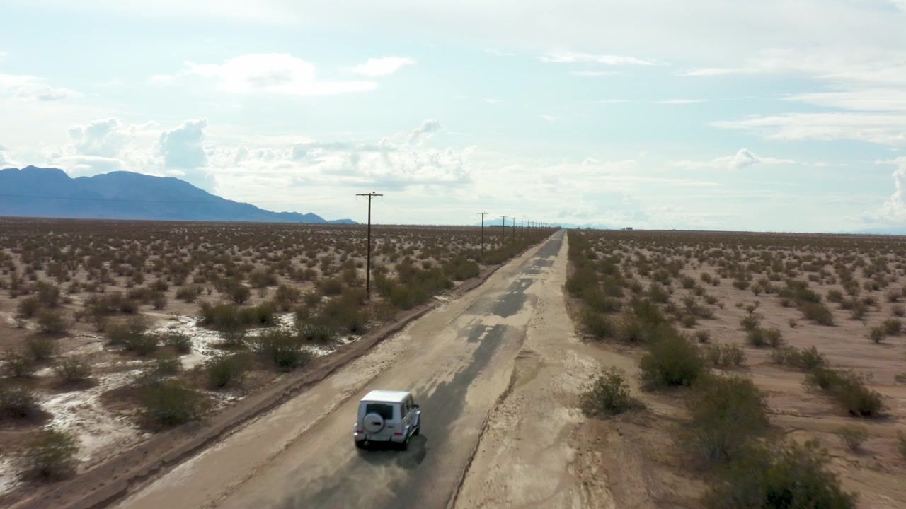 Aéreo: Sedán plateado alejándose por una carretera desierta.