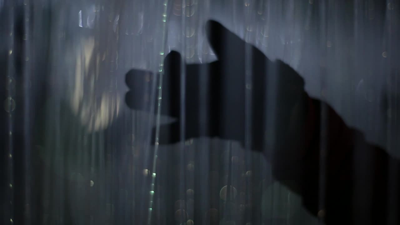 Guy is playing with hand silhouette against light. Colorful lit upstrings are hanging around, some of them nicely blurred out. Color changes. Footage in HD