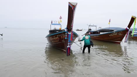 person interacts with boat on krabi beach