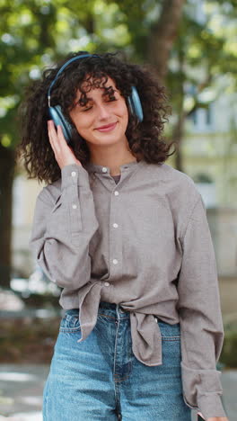 Woman-in-wireless-headphones-choosing-listening-music-song-in-smartphone-application-on-city-street