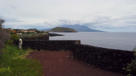 paisaje revelador en azores, isla faial, con el océano golpeando la costa y las montañas en el fondo