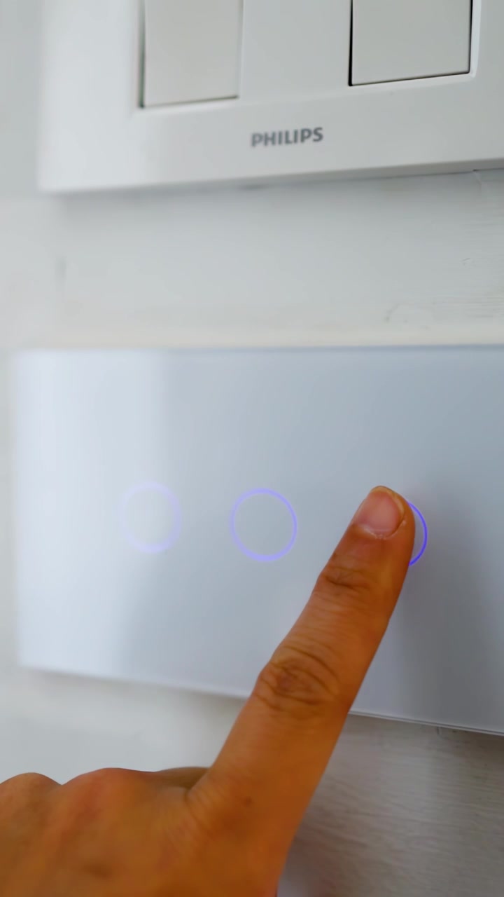 Close-up shot of a finger pressing buttons on a smart home touch control panel