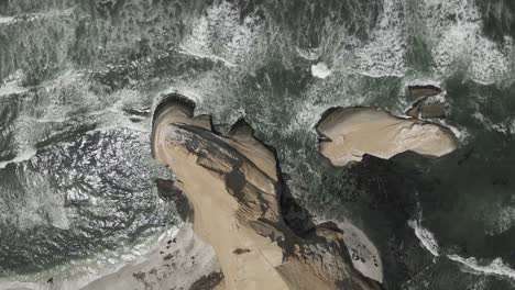 vertical aerial view of sand sea cliffs and eroded sea stack in peru